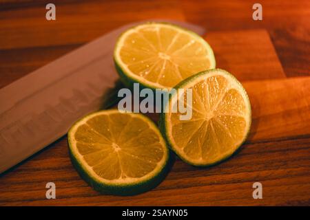 Lemon and Lime being sliced on wooden chopping surface Stock Photo