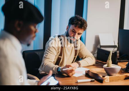 Two colleagues engaged in a focused business meeting at a modern office desk Stock Photo