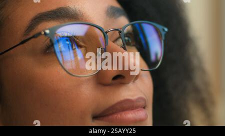 Close up female face woman African American girl in eyeglasses looking away glasses reflection smile calm gen z ethnic student business lady Stock Photo