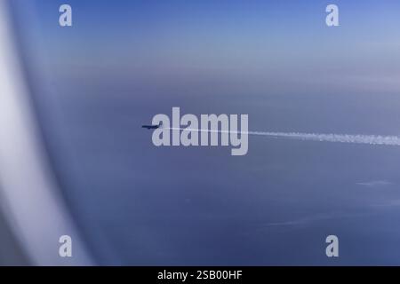 View of the Persian Gulf from the aeroplane window. Sun and clouds over the sea. Aeroplane above the clouds with vapour trails. Flight with the airlin Stock Photo