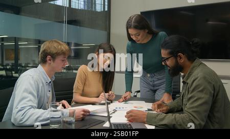 Team leader coworkers planning work analyzing corporate documents reviewing statistics learn data charts graphs group diverse businessmen Stock Photo