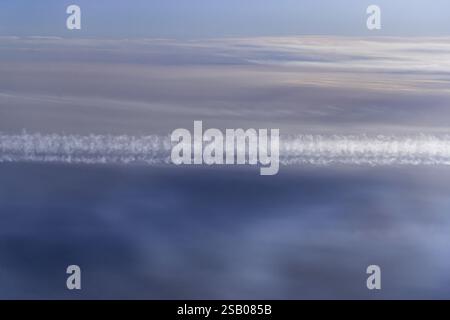 View of the Persian Gulf from the aeroplane window. Sun and clouds over the sea. Aeroplane above the clouds with vapour trails. Flight with the airlin Stock Photo