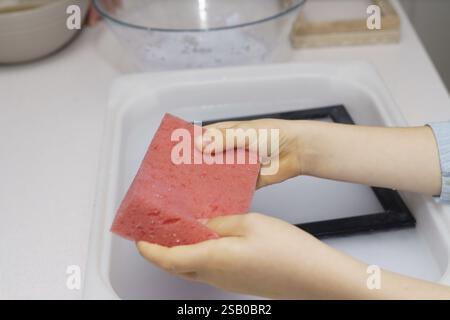 A boy holds a red sponge doing handicraft work at home Stock Photo