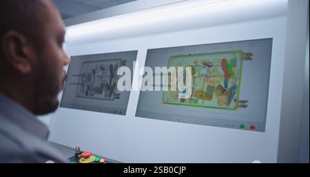 African American Security Officer Controls Luggage Screening on Computer. PC Monitors Showing Modern Software for Advanced X-ray Scanning at Airport Security Checkpoint for Plane Flight. Close Up. Stock Photo