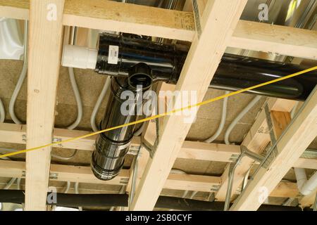 First floor from below showing underfloor heating pipework and black bathroom waste pipes through posi joists, as well as new electrical wiring. Stock Photo