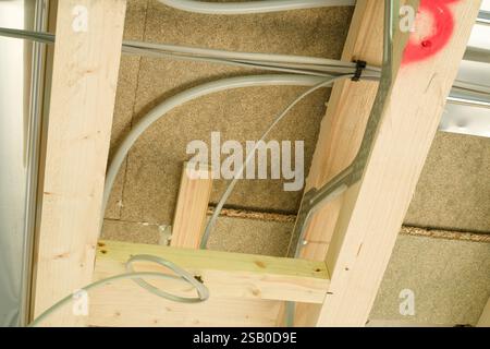 Underfloor heating pipes and new electrical wires through ceiling joists. First fix in a new build property in the UK. Stock Photo