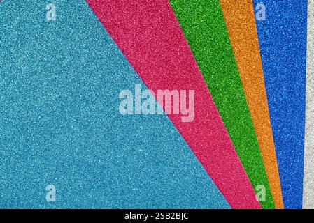 Glitter sheets of different colors overlapped one on top of the other. Textured background. Materials. Stock Photo