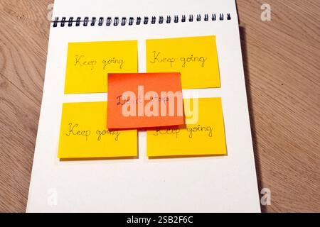 A yellow and orange sticky note with the words "don't stop" written on it. The note is placed in the middle of four other yellow and sticky notes with Stock Photo