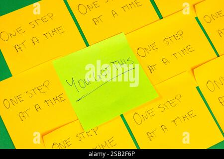 A green sticky note with the word "you got this" written on it. There are several other yellow sticky note with different words on them. Concept photo Stock Photo