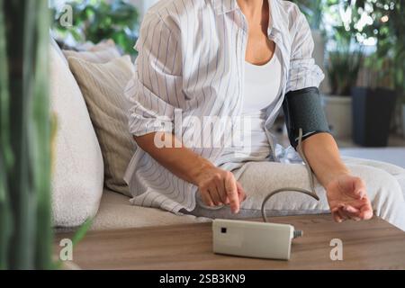 An elderly woman with hypertension measures her own blood pressure at ...