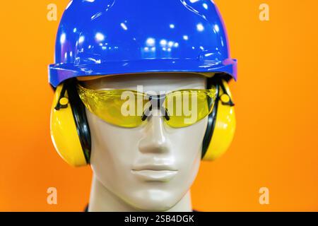 Personal protective equipment (PPE) mannequin equipped with essential safety gear, including a blue hard hat, yellow ear protection, and tinted safety glasses. Ideal for showcasing construction or industrial safety equipment. Stock Photo