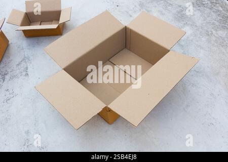 Open empty brown cardboard box on concrete floor Stock Photo