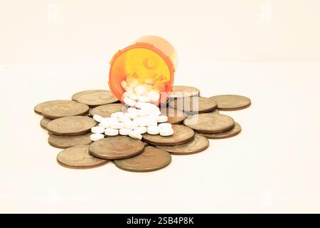 A Prescription bottle is on its side spilling out tablets over a pile of silver dollars. Concept is the expense of prescriptions. Stock Photo
