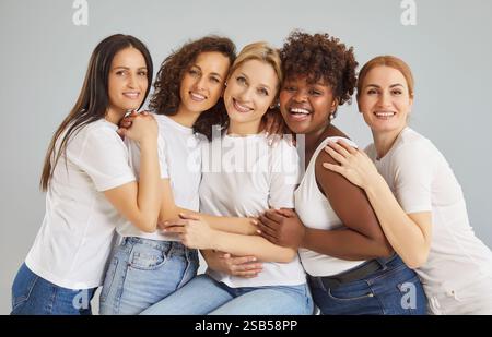 Happy diverse young women looking at camera isolated on grey studio background. Stock Photo
