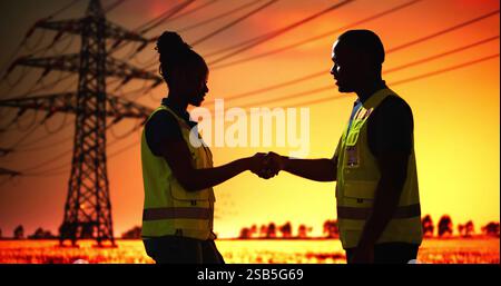 Electrician Workers Shaking Hands Near High Voltage Circuit Line Tower Stock Photo
