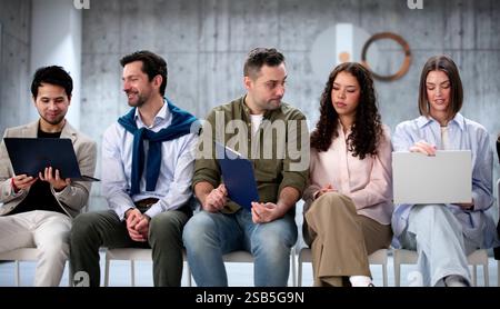 Job seekers anxiously await interviews in diverse office environment. Businessman dismissed. Stock Photo