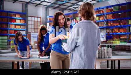 Smiling young volunteer giving food to diverse group of people. Stock Photo