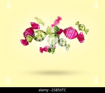 Candies in bright wrappers falling on beige background Stock Photo