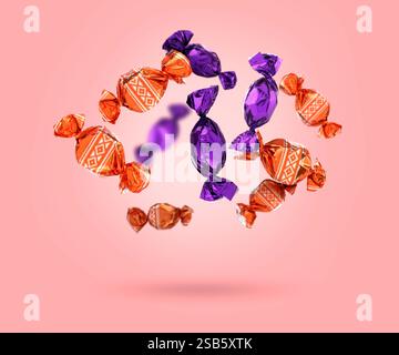 Candies in bright wrappers falling on pink background Stock Photo