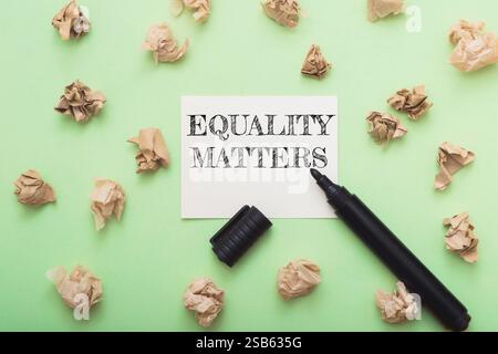 Equality matters is written on a piece of paper. A black marker is on the paper. The paper is on a green surface Stock Photo