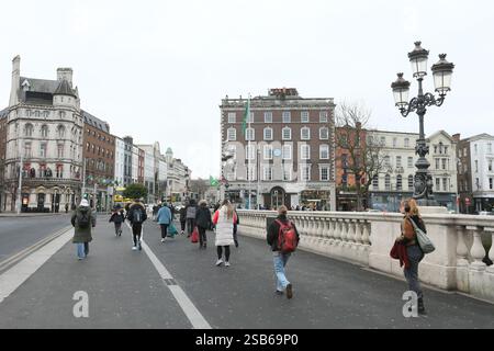 Dublin, Ireland - 22nd January 2025 - People walking on the footpath on O'Connell Bridge with the bridge lamps visible in the background Stock Photo