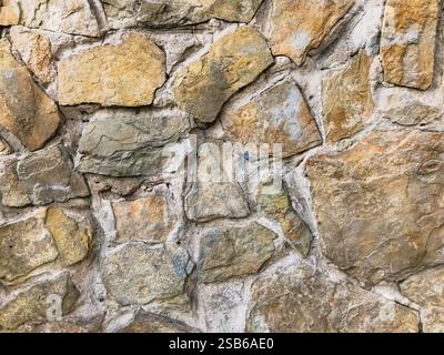 Wall made of stone with a few blue spots on it. The wall is brown and gray Stock Photo