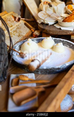 Unbaked dough balls shaped for bear-themed bread, resting on a flour-dusted tray, with a rolling pin and honey drizzler nearby Stock Photo