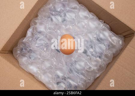 Chicken egg on air cushion bubble wrap background, insidee a cardboard box Stock Photo