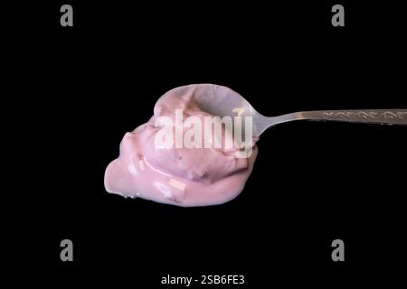 Spoon full of pink strawberry yogurt isolated on black Stock Photo