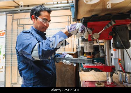 Latin worker drilling metal in workshop using bench drill press Stock Photo