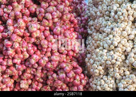 vibrant display of fresh red shallots and white garlic stacked side by side, showcasing their natural textures and colors. This image perfectly captur Stock Photo