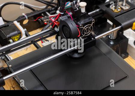 This is a detailed closeup view of a 3D printer equipped with a cooling fan on top of it, showcasing its intricate design and components Stock Photo