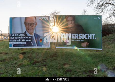 Wahlplakate von CDU und Grünen im Gegenlicht 01.02.25, Hünfelden: Symbolfoto, Illustrationsbild, Symbolbild, Illustrationsfoto, Alltagsszene Wahlplakate von CDU und Grünen im Gegenlicht Zwei Wahlplakate stehen nebeneinander auf einer Wiese im Abendlicht. Links ist ein Plakat der CDU mit Friedrich Merz und dem Slogan Für ein Land, auf das wir wieder stolz sein können. Rechts befindet sich ein Plakat der Grünen mit Robert Habeck und dem Wort ZUVERSICHT. Die tief stehende Sonne scheint direkt zwischen den Plakaten hindurch und erzeugt eine starke Lichtstimmung mit Sonnenstrahlen. Am 23. Februar 2 Stock Photo