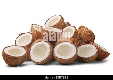 pile of coconuts cut in half isolated white background, brown fibrous husk and inner white flesh visible, abundance and freshness concept Stock Photo