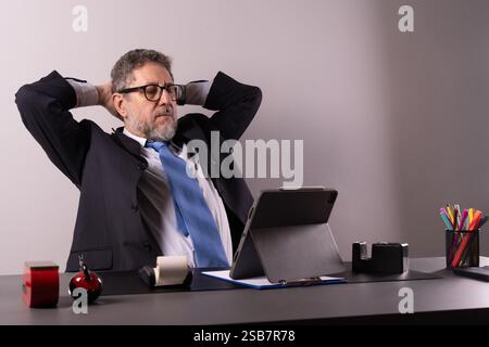 Businessman stretching and taking a break at his office desk, highlighting workplace relaxation and mental well-being. Stock Photo