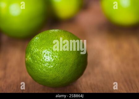 Fresh whole key lime citrus fruit on wooden board, photographed with natural light (Very Shallow Depth of Field, Focus on the front of the lime) Stock Photo