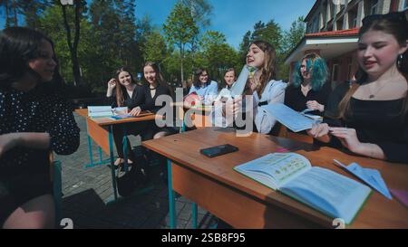 Cheerful students are actively participating in an outdoor lesson, enjoying the pleasant weather and engaging in their studies Stock Photo