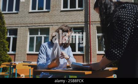 High school students collaborating on a project outdoors on a sunny day Stock Photo