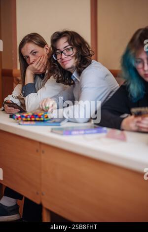 Teenage students take a break from studying, relax at their school desk, and enjoy some downtime Stock Photo