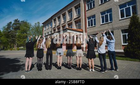 Group of students waving goodbye to school on their last day, celebrating the end of the academic year Stock Photo