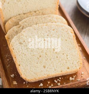 Slices of fresh homemade white bread made by a bread making machine, served on wooden board (Selective Focus, Focus in the middle of the image) Stock Photo