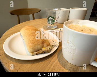 table in starbucks coffee shop with branded mug and cup and tuna melt panini Stock Photo