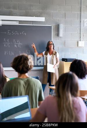 View from behind a group of multiracial students taking notes in a classroom Stock Photo