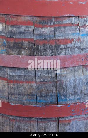 A wooden barrel with red and blue stripes. The barrel is old and has a worn look to it Stock Photo