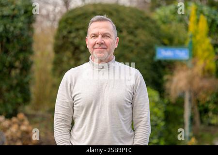 A middle-aged man with short gray hair and a neatly trimmed beard stands with a calm and confident expression. Stock Photo