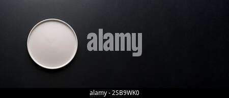Top view of empty ceramic white plate on black background Stock Photo