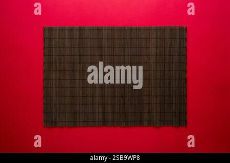 Empty bamboo mat on red background. Chinese food concept background Stock Photo