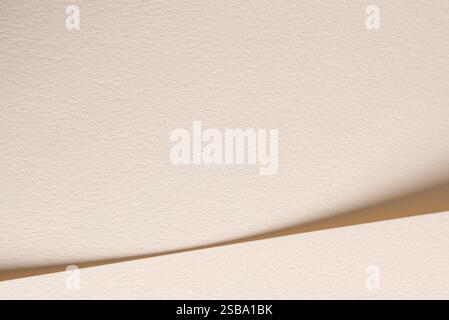 A beige paper background with soft tones and gentle curves, creating a minimalist and natural aesthetic. The subtle shadows and neutral color palette Stock Photo