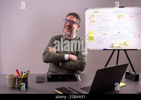 Business executive explaining market performance trends on a whiteboard, analyzing revenue growth and financial projections in a corporate setting. Stock Photo