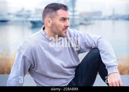Side view Confident Man in Casual Outfit Relaxing Outdoors Near Marina Stock Photo